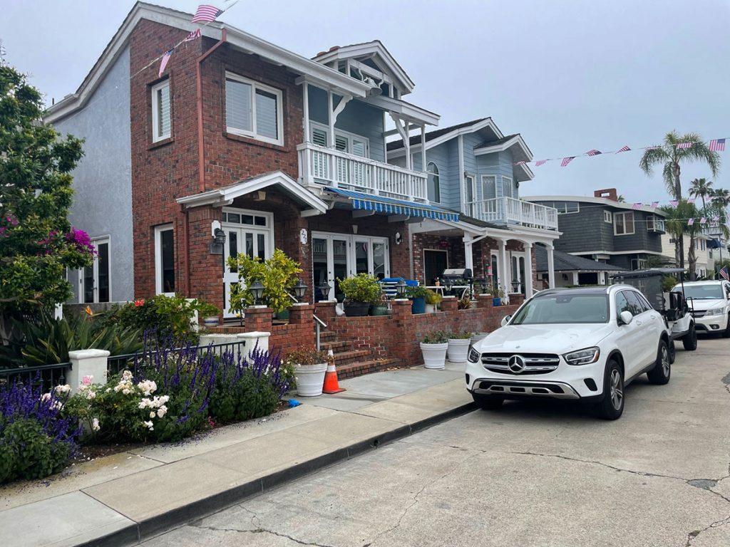 A two story red brick house with a white rails balcony in Newport Beach CA